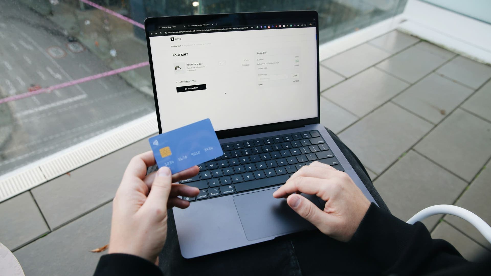 Hands holding a bank card over a laptop while paying online